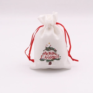 Détail du sac cadeau de Noël en lin blanc avec cordon rouge et motif sapin imprimé