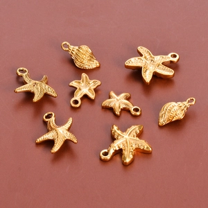 Macro shot of 8 golden starfish and seashell charms made of polished stainless steel