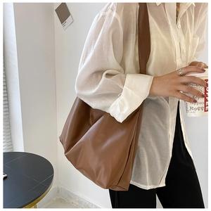Minimalist large-capacity coffee brown faux leather tote bag worn by a model for commuting
