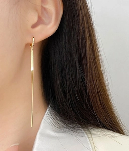 Close-up of elegant gold tassel snake chain earrings worn by a model in a minimal style