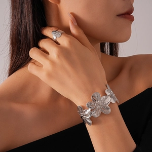Macro shot of silver textured flower cuff bracelet and ring set for women