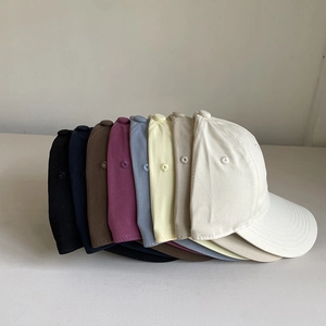 Close-up of stacked colorful cotton baseball caps with embroidered vents and twill texture