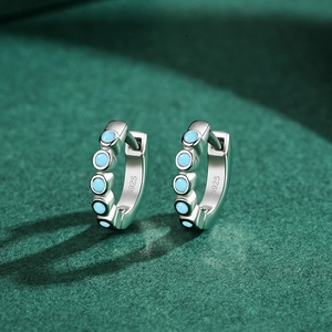 Créoles élégantes en argent S925 avec pierres turquoise sur fond vert foncé texturé