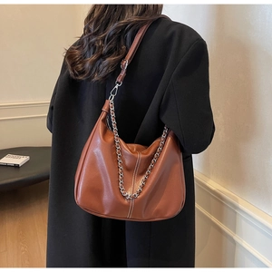 Detail of caramel hobo bag featuring silver chain decor and white contrast stitching