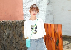 Detail of light blue popsicle shaped cup with cute strap worn by a model outdoors
