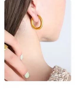 Close-up of a model wearing smooth 18K gold plated U-shaped chunky hoop earrings