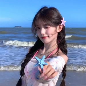 Pink and blue matte resin starfish hair clips worn by a model on a sunny summer beach