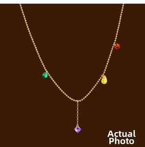 Close-up of golden ball chain necklace featuring colorful multi-shaped gemstone charms