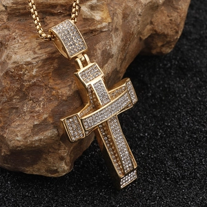 Detail of a gold hip-hop cross pendant with micro-pave diamonds on a textured stone base