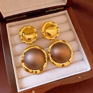 Close-up of vintage golden hammered earrings with brown center in a wooden jewelry box