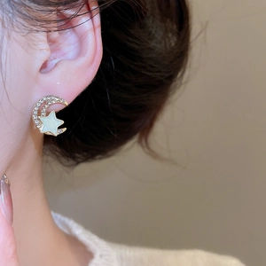 Close-up of elegant gold crescent moon and star stud earrings with white rhinestones