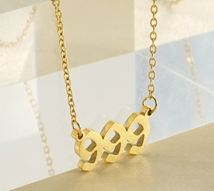 Macro shot of 18k gold plated stainless steel 999 pendant on acrylic block display