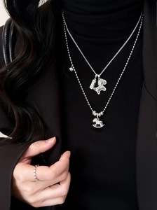 Détail d'un collier double épaisseur argenté avec pendentifs chevaux en zircon sur noir