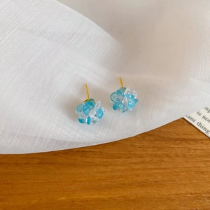 Detailed close-up of crystal flower stud earrings with blue beads and gold pins