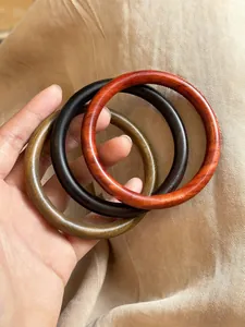 Vue détaillée de trois bracelets ronds minimalistes en bois marron foncé et noir mat