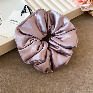 Détail d'un chouchou en satin violet avec plis doux et étiquette d'accessoire fait main