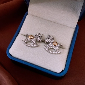 Macro view of crystal encrusted rocking horse stud earrings in a luxury jewelry box