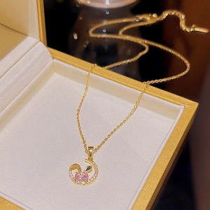 Detailed close-up of 18K gold rabbit necklace with pink stone in a premium jewelry box