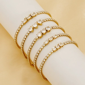Détail de cinq bracelets de tennis dorés avec diverses coupes de zircon sur un support