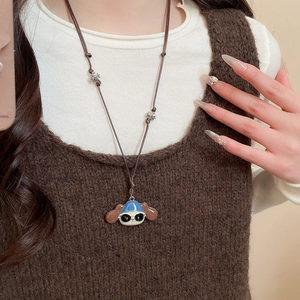 Close-up of cute cartoon dog pendant with blue sun hat on a brown leather cord