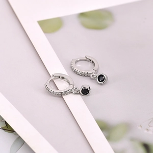 Detail of silver hoop earrings with sparkling white stones and round black gems