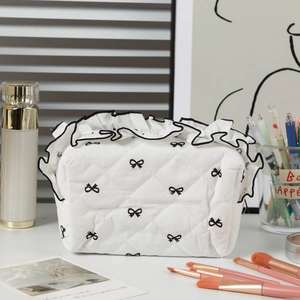 Detail of quilted cotton makeup bag with black bow print and ruffled lace edges