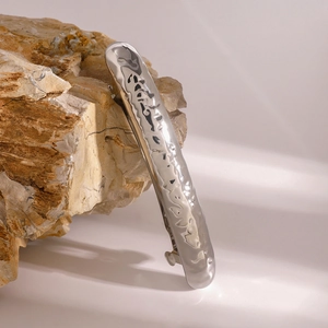 Close-up of silver hammered metal hair clip on stone with natural soft sunlight