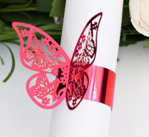 Macro shot of pink metallic butterfly napkin ring with hollowed design on white napkin