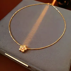 Gold plated zircon flower necklace on blue velvet box with soft sunlight shadow
