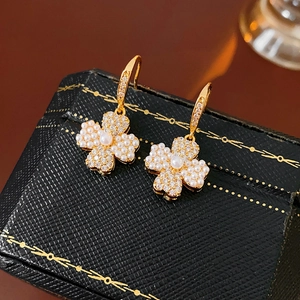 Detail of clover earrings with faux pearls and zircons on a luxury jewelry box