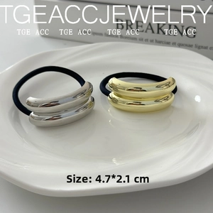 Detail showing smooth gold and silver metal hair ties measuring 4.7x2.1cm on a white plate