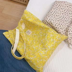 Close-up of yellow floral cotton tote bag featuring a white woven label detail