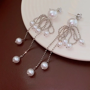 Gros plan de boucles d'oreilles pampilles argentées avec perles blanches et zircons