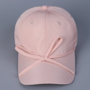 Close-up of a pink satin baseball cap featuring a decorative large bow and breathable eyelets