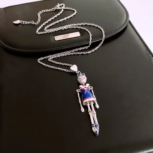 Detail of movable silver pendant necklace with blue sailor suit and red rhinestones