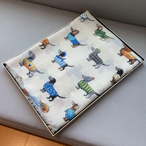 Detail of cotton linen scarf with cute cartoon dachshund print and fringe edges in a gift box