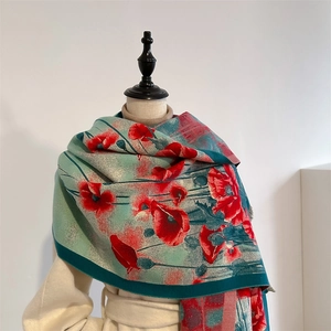 Nahaufnahme des weichen türkisfarbenen Schals mit roten Mohnblumen und eleganten Fransen
