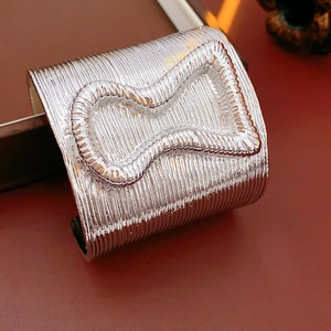 Macro shot of silver wide open bangle featuring linear textures and hourglass pattern