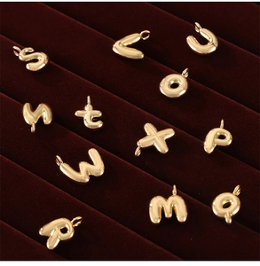 Macro view of gold-plated puffy letter pendants on a luxury red velvet jewelry display