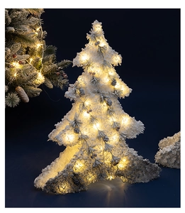 Detailed view of flocked Christmas tree with warm LED lights, pine cones, and red berries