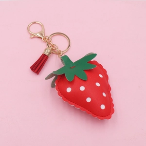 Macro shot of red leather strawberry keychain with gold hardware and red tassel detail