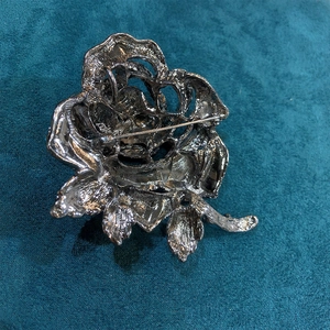 Back view of rose flower brooch showing pin fastener and vintage metal texture details