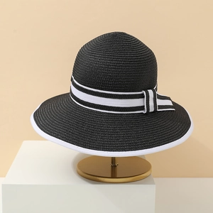Detail of black straw sun hat featuring elegant white ribbon trim and chic side knot
