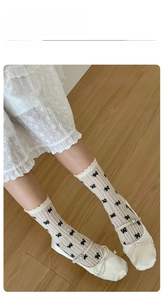 Close-up of ballet-style cream socks with black bows and lace dress details