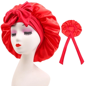 Detail of red satin nightcap featuring a silk-like bow and adjustable long ribbons
