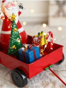 Close-up of red iron Christmas sleigh cart with Santa figurine and warm LED lights