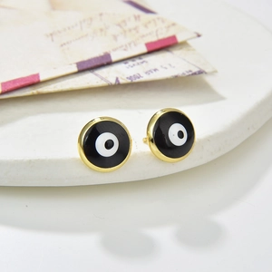 Detailed view of Evil Eye stud earrings with gold rim on a white textured display