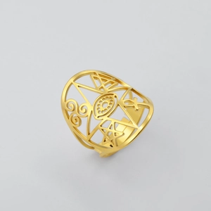 Close-up of golden hollow ring with eye and geometric symbols on a gray background