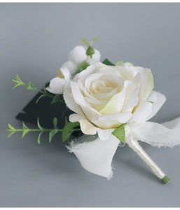 Détail d'une boutonnière rose blanche avec feuilles vertes, rubans de soie et glands