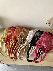 Detail of colorful woven mesh tote bags with wooden ring handles in various vibrant colors